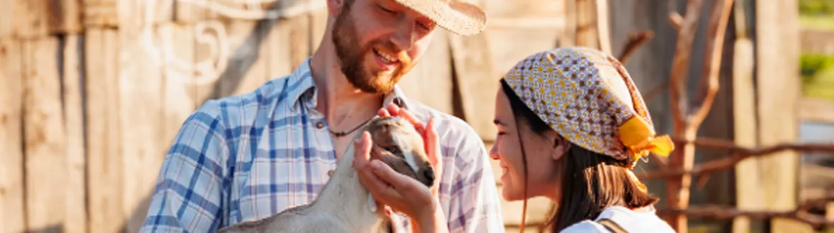Two goat farmers holding a baby goat
